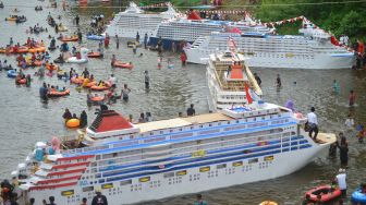 Sejumlah warga mendorong kajang (perahu yang dihias serupa kapal pesiar) saat digelarnya tradisi Bakajang di Sungai Batang Mahek, Nagari Gunuang Malintang, Kabupaten Limapuluhkota, Sumatera Barat, Kamis (5/5/2022). [ANTARA FOTO/Iggoy el Fitra]