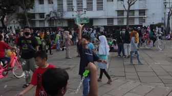 Warga bermain gelembung sabun saat berwisata di Taman Fatahillah, Kota Tua, Jakarta, Kamis (5/5/2022). [Suara.com/Angga Budhiyanto]