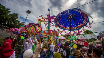 Warga merapikan payung yang telah dihias saat tradisi Batumbang Apam di halaman Masjid Al Munawwarah, Barabai, Kabupaten Hulu Sungai Tengah, Kalimantan Selatan, Rabu (4/5/2022). [ANTARA FOTO/Bayu Pratama S/tom]
