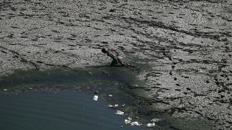 Seorang anak laki-laki berjalan melintasi sepetak dasar sungai Yamuna yang kering pada hari musim panas di New Delhi, India, pada (2/5/2022). [Sajjad HUSSAIN / AFP]