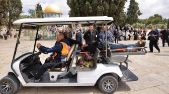 Anggota Bulan Sabit Merah Palestina mengevakuasi seorang pria selama bentrokan dengan pasukan keamanan Israel di kompleks Masjid Al-Aqsa di Yerusalem, pada (5/5/2022). [AHMAD GHARABLI / AFP]