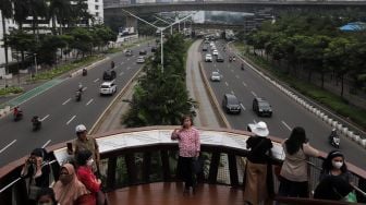 Warga berfoto di Jembatan Penyeberangan Orang (JPO) Pinisi Karet-Sudirman, Jakarta, Sabtu (7/5/2022). [Suara.com/Angga Budhiyanto]