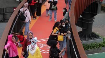 Warga berswafoto di Jembatan Penyeberangan Orang (JPO) Pinisi Karet-Sudirman, Jakarta, Sabtu (7/5/2022). [Suara.com/Angga Budhiyanto]