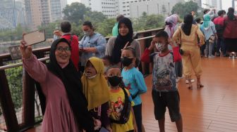 Warga berswafoto di Jembatan Penyeberangan Orang (JPO) Pinisi Karet-Sudirman, Jakarta, Sabtu (7/5/2022). [Suara.com/Angga Budhiyanto]