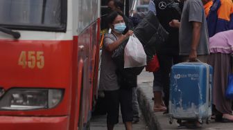 Pemudik membawa barang bawaan setibanya di Terminal Kampung Rambutan, Jakarta, Sabtu (7/5/2022). [Suara.com/Angga Budhiyanto]