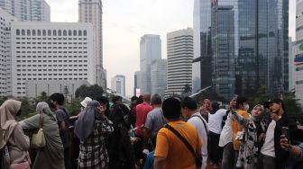 Warga berfoto di Jembatan Penyeberangan Orang (JPO) Pinisi Karet-Sudirman, Jakarta, Sabtu (7/5/2022). [Suara.com/Angga Budhiyanto]