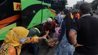 Pemudik menurunkan barang bawaan dari bagasi bus setibanya di Terminal Kampung Rambutan, Jakarta, Sabtu (7/5/2022). [Suara.com/Angga Budhiyanto]