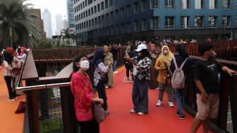 Warga menikmati suasana di Jembatan Penyeberangan Orang (JPO) Pinisi Karet-Sudirman, Jakarta, Sabtu (7/5/2022). [Suara.com/Angga Budhiyanto]