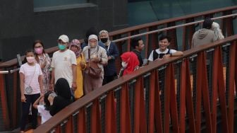 Warga berfoto di Jembatan Penyeberangan Orang (JPO) Pinisi Karet-Sudirman, Jakarta, Sabtu (7/5/2022). [Suara.com/Angga Budhiyanto]