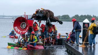 Para peserta mengayuh patung kinetik mereka di atas air saat ajang Lomba Balap Patung Kinetik yang digelar Museum Seni Visioner Amerika di Pelabuhan Baltimore, Maryland, Amerika Serikat, Sabtu (7/5/2022). [Jose Luis Magana / AFP]
