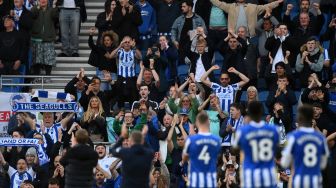 Para pemain Brighton merayakan kemenangan dengan pendukung mereka usai pertandingan sepak bola Liga Premier Inggris antara Brighton dan Manchester United di Stadion American Express Community, Brighton, Inggris, Sabtu (7/5/2022). [Glyn KIRK / AFP]
