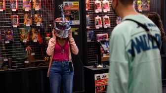 Seorang pengunjung mencoba helm karakter Lord Zeed saat menghadiri Comic Fair ke-40 di Barcelona, Spanyol, Sabtu (7/5/2022). [Josep LAGO / AFP]