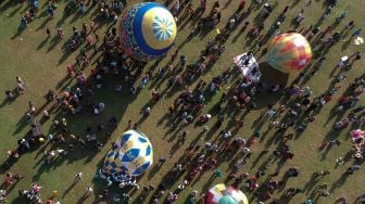 Foto udara sejumlah warga menerbangkan balon udara yang ditambatkan di tanah saat "Balloon Attraction Pekalongan 2022" di Lapangan Mataram, Kota Pekalongan, Jawa Tengah, Minggu (8/5/2022). [ANTARA FOTO/Harviyan Perdana Putra/aww]
