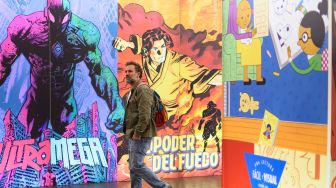 Seorang pengunjung berjalan melewati mural saat menghadiri Comic Fair ke-40 di Barcelona, Spanyol, Sabtu (7/5/2022). [Josep LAGO / AFP]