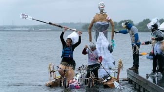 Para peserta mengayuh patung kinetik mereka di atas air saat ajang Lomba Balap Patung Kinetik yang digelar Museum Seni Visioner Amerika di Pelabuhan Baltimore, Maryland, Amerika Serikat, Sabtu (7/5/2022). [Jose Luis Magana / AFP]
