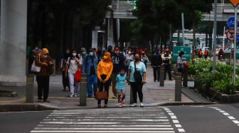 Sejumlah pekerja berjalan di trotoar saat jam pulang kerja di Jalan Sudirman, Jakarta Pusat, Senin (9/5/2022). [Suara.com/Alfian Winanto]