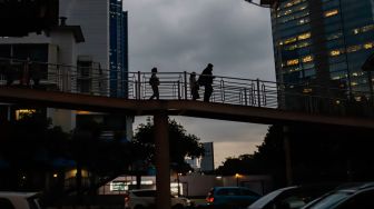 Sejumlah pekerja berjalan di Jembatan Penyeberangan Orang (JPO) saat jam pulang kerja di Jalan Sudirman, Jakarta Pusat, Senin (9/5/2022). [Suara.com/Alfian Winanto]