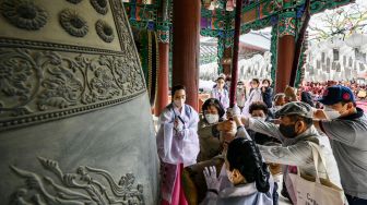 Para jamaah membunyikan lonceng besar setelah kebaktian saat peraayan Hari Kelahiran Buddha di Kuil Jogye, Seoul, Korea Selatan, Minggu (8/5/2022). [ANTHONY WALLACE / AFP]
