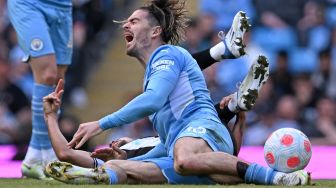 Gelandang Newcastle United Bruno Guimaraes (kanan) menjegal gelandang Manchester City Jack Grealish saat pertandingan sepak bola Liga Premier Inggris antara Manchester City dan Newcastle United di Stadion Etihad, Manchester, Inggris, Minggu (8/5/2022). [Paul ELLIS / AFP]
