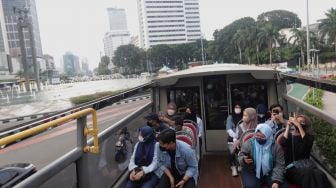 Warga berada di atas bus wisata gratis Transjakarta dengan atap terbuka di Jakarta, Selasa (10/5/2022). [Suara.com/Angga Budhiyanto]