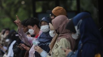 Warga menunggu kedatangan bus wisata gratis Transjakarta di Jakarta, Selasa (10/5/2022). [Suara.com/Angga Budhiyanto]