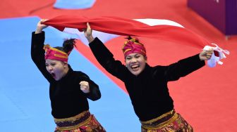 Pesilat Indonesia Riska Hermawan (kiri) dan Ririn Rinasih (kanan) berpose dengan medali emasnya yang diraih pada final Seni Ganda Putri Pencak Silat SEA Games 2021 Vietnam di Bac Tu Liem Sport Center, Hanoi, Rabu (11/5/2022).  ANTARA FOTO/Zabur Karuru