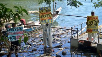 Aktivis lingkungan WALHI Sumbar dan Tim Ekspedisi Sungai Nusantara (ESN) melakukan aksi protes dengan mengembangkan poster terkait pencemaran sungai di Sungai Batang Arau, Padang, Sumatera Barat, Rabu (11/5/2022).  ANTARA FOTO/Iggoy el Fitra