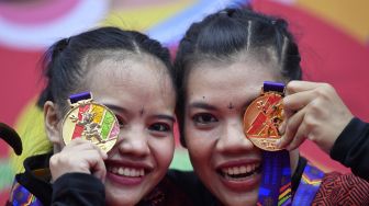 Pesilat Indonesia Riska Hermawan (kiri) dan Ririn Rinasih (kanan) berpose dengan medali emasnya yang diraih pada final Seni Ganda Putri Pencak Silat SEA Games 2021 Vietnam di Bac Tu Liem Sport Center, Hanoi, Rabu (11/5/2022).  ANTARA FOTO/Zabur Karuru