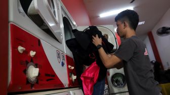 Pekerja membersihkan baju pelanggan di Jourdan Laundry Expert, Ampera Raya, Jakarta, Rabu (11/5/2022). [Suara.com/Angga Budhiyanto]