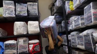 Pekerja mengambil baju milik pelanggan di Jourdan Laundry Expert, Ampera Raya, Jakarta, Rabu (11/5/2022). [Suara.com/Angga Budhiyanto]