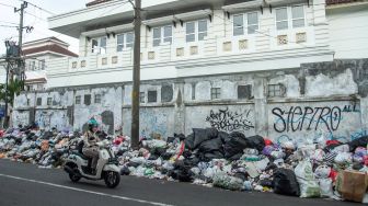 Pengendara melintas di dekat tumpukan sampah di kawasan Patuk, Yogyakarta, Rabu (11/5/2022). ANTARA FOTO/Hendra Nurdiyansyah