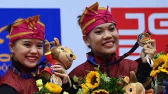 Pesilat Indonesia Riska Hermawan (kiri) dan Ririn Rinasih (kanan) berpose dengan medali emasnya yang diraih pada final Seni Ganda Putri Pencak Silat SEA Games 2021 Vietnam di Bac Tu Liem Sport Center, Hanoi, Rabu (11/5/2022).  ANTARA FOTO/Zabur Karuru