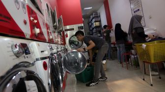 Pekerja membersihkan baju pelanggan di Jourdan Laundry Expert, Ampera Raya, Jakarta, Rabu (11/5/2022). [Suara.com/Angga Budhiyanto]