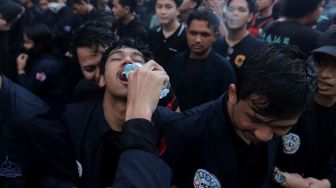 Massa mahasiswa Universitas Trisakti memberikan minuman kepada temannya saat menggelar aksi unjuk rasa memperingati Tragedi Trisakti 1998 di kawasan Patung Kuda Arjuna Wiwaha, Jakarta, Kamis (12/5/2022). [Suara.com/Angga Budhiyanto] 