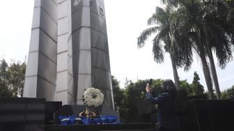 Seorang mahasiswi mengambil gambar Monumen Reformasi 12 Mei 1998 Universitas Trisakti saat peringatan Tragedi Trisakti 12 Mei 1998 di Jakarta, Kamis (12/5/2022). [Suara.com/Angga Budhiyanto]