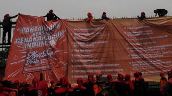 Massa buruh memasang spanduk saat melakukan aksi unjuk rasa di depan gedung DPR RI, Jakarta, Sabtu (14/5/2022). [Suara.com/Angga Budhiyanto]