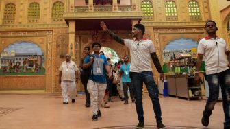 Seorang pemandu memimpin sekelompok pengunjung selama tur di Taman Bollywood di Filmcity Mumbai, India, Jumat (13/5/2022). [SUJIT JAISWAL / AFP]