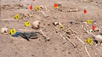 Tengkorak manusia yang digali dari kuburan massal tergeletak di tanah di Kota Najaf, Irak, Sabtu (14/5/2022). [AFP]
