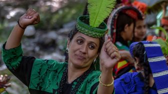 Wanita suku Kalash yang mengenakan pakaian tradisional berjalan menuju rumah kerabat mereka untuk mengumpulkan susu dan menari sebagai bagian dari ritual pada hari pertama festival 'Joshi' di desa Bumburet, Pakistan, Sabtu (14/5/2022). [Abdul MAJEED / AFP]