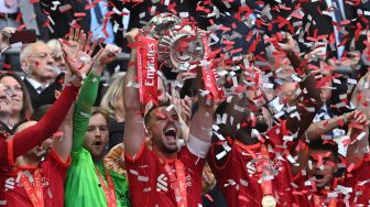 Gelandang Liverpool Jordan Henderson (kanan depan) mengangkat trofi Piala FA ketika selebrasi dengan rekan satu timnya setelah memenangkan pertandingan sepak bola final Piala FA Inggris antara Chelsea dan Liverpool di Stadion Wembley, London, Inggris (Sabtu 14/5/2022). [Ben Stansall / AFP]