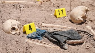 Tengkorak manusia yang digali dari kuburan massal tergeletak di tanah di Kota Najaf, Irak, Sabtu (14/5/2022). [AFP]