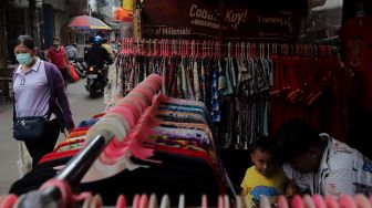 Warga melintasi lapak pedagang kaki lima (PKL) di Pasar Petak Sembilan, Glodok, Jakarta, Senin (16/5/2022). [Suara.com/Angga Budhiyanto]