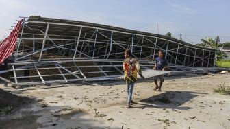 Warga merapikan sisa puing restoran yang rusak akibat angin kencang di Bedahan, Depok, Jawa Barat, Senin (16/5/2022). ANTARA FOTO/Asprilla Dwi Adha