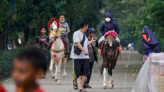 Anak-anak berwisata sambil menunggangi kuda di kawasan Kanal Banjir Timur (KBT), Jakarta Timur, Senin (16/5/2022). [Suara.com/Alfian Winanto] 