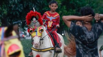 Seorang anak berwisata sambil menunggangi kuda di kawasan Kanal Banjir Timur (KBT), Jakarta Timur, Senin (16/5/2022). [Suara.com/Alfian Winanto] 
