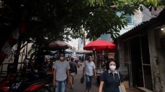 Warga melintasi lapak pedagang kaki lima (PKL) di Pasar Petak Sembilan, Glodok, Jakarta, Senin (16/5/2022). [Suara.com/Angga Budhiyanto]