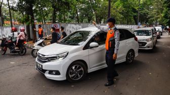 Petugas mengatur kendaraan saat melakukan uji coba rekayasa lalu lintas di sekitar kawasan Tebet Eco Park, Jakarta Selatan, Senin (16/5/2022). [Suara.com/Alfian Winanto]
