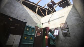 
Warga merapikan barang-barang yang tertimpa atap rumah akibat angin kencang di Bedahan, Depok, Jawa Barat, Senin (16/5/2022). ANTARA FOTO/Asprilla Dwi Adha
