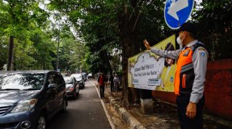 Petugas mengatur kendaraan saat melakukan uji coba rekayasa lalu lintas di sekitar kawasan Tebet Eco Park, Jakarta Selatan, Senin (16/5/2022). [Suara.com/Alfian Winanto]
