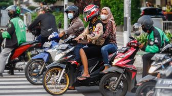 Pengendara motor berhenti saat lampu merah Jalan Thamrin, Jakarta Pusat, Selasa (17/5/2022). [Suara.com/Alfian Winanto]